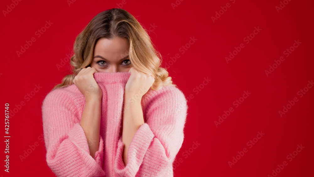 A young sweet and smiling blonde woman in a pink knitted sweater A young sweet and smiling blonde woman in a pink knitted sweater