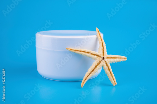 A jar of cream isolated on a blue background with seashells and a starfish