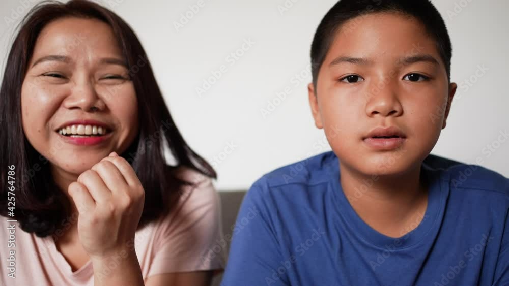 slow motion scene asian mother and son greeting while use video call to family in home for technology and internet lifestyle concept slow motion scene asian mother and son greeting while use video call to family in home for technology and internet lifestyle concept