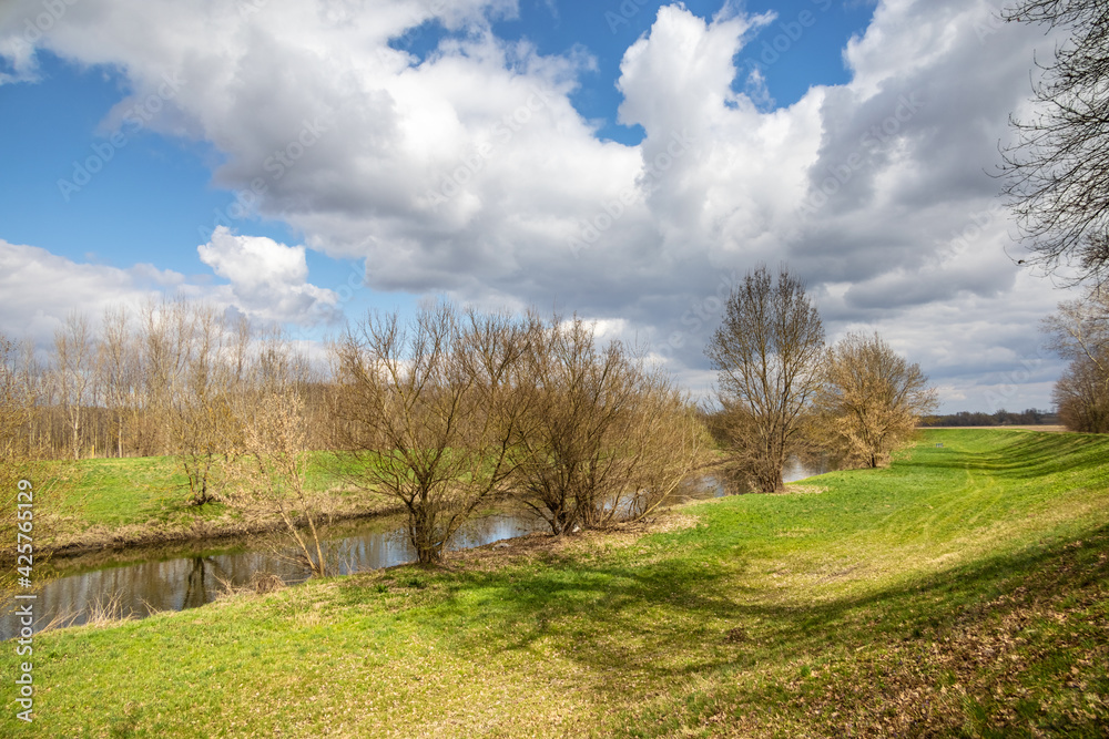 Spring landscape with river, trees and cloudy sky