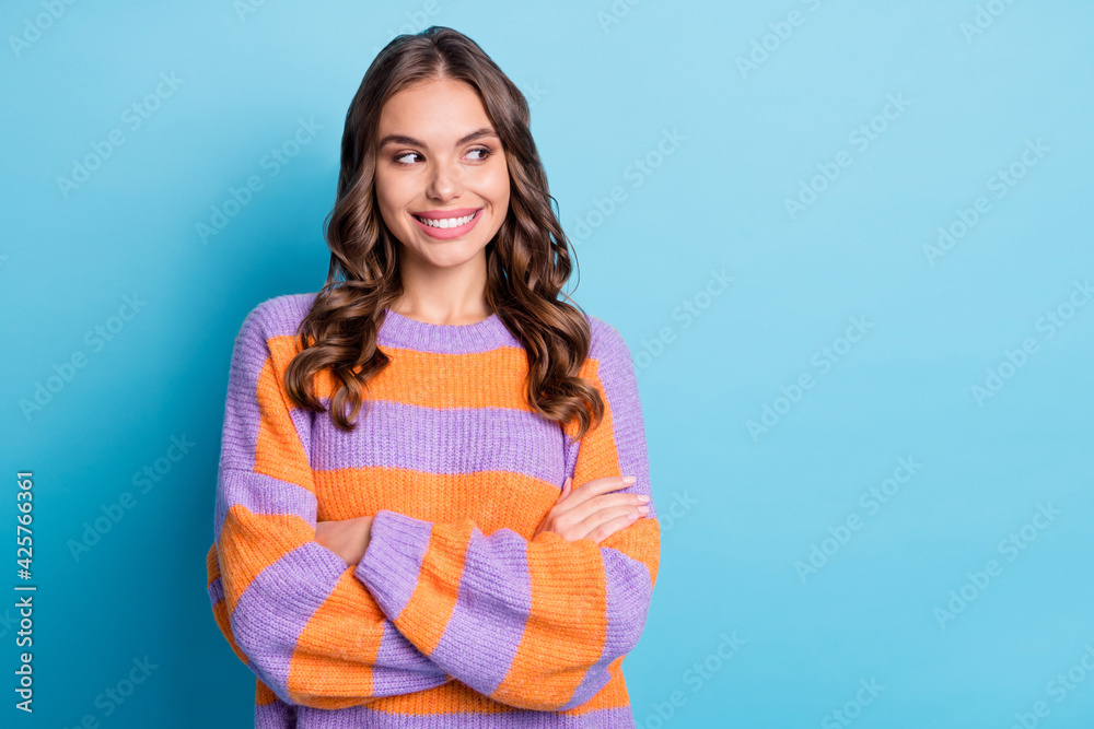 Portrait of attractive cheerful wavy-haired girl folded arms looking aside copy space isolated over bright blue color background Portrait of attractive cheerful wavy-haired girl folded arms looking aside copy space isolated over bright blue color background
