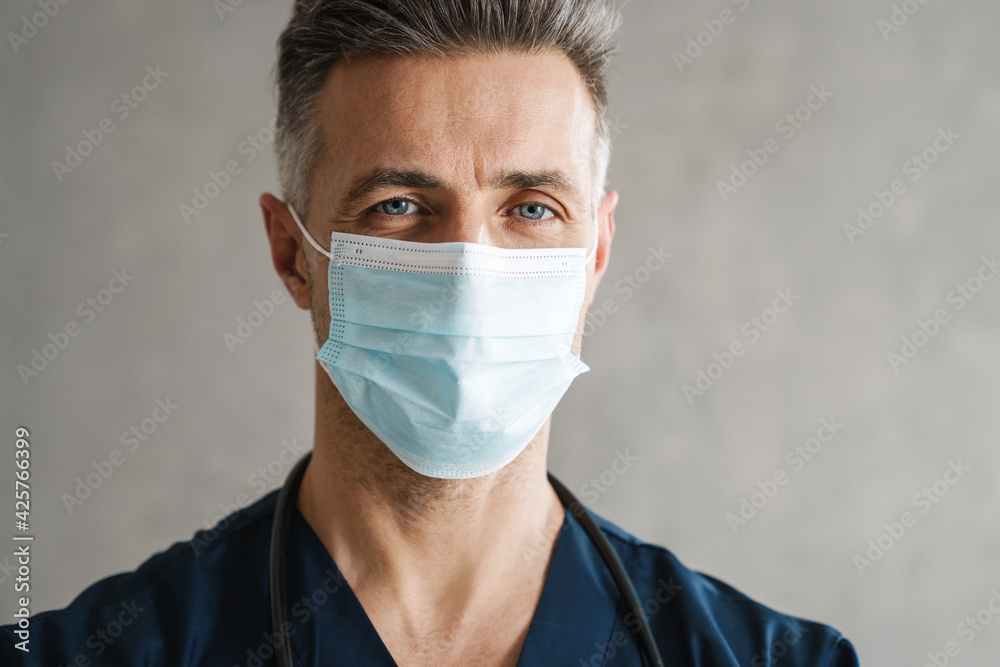 Confident mid aged doctor in protective medical mask Confident mid aged doctor in protective medical mask