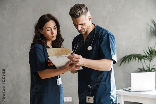 Two doctors in medical uniforms discussing patient anamnesis