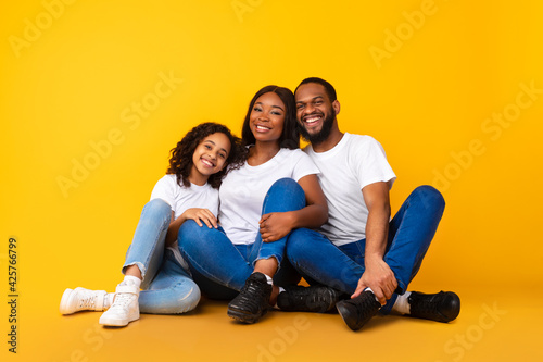 African American man hugging his smiling wife and daughter