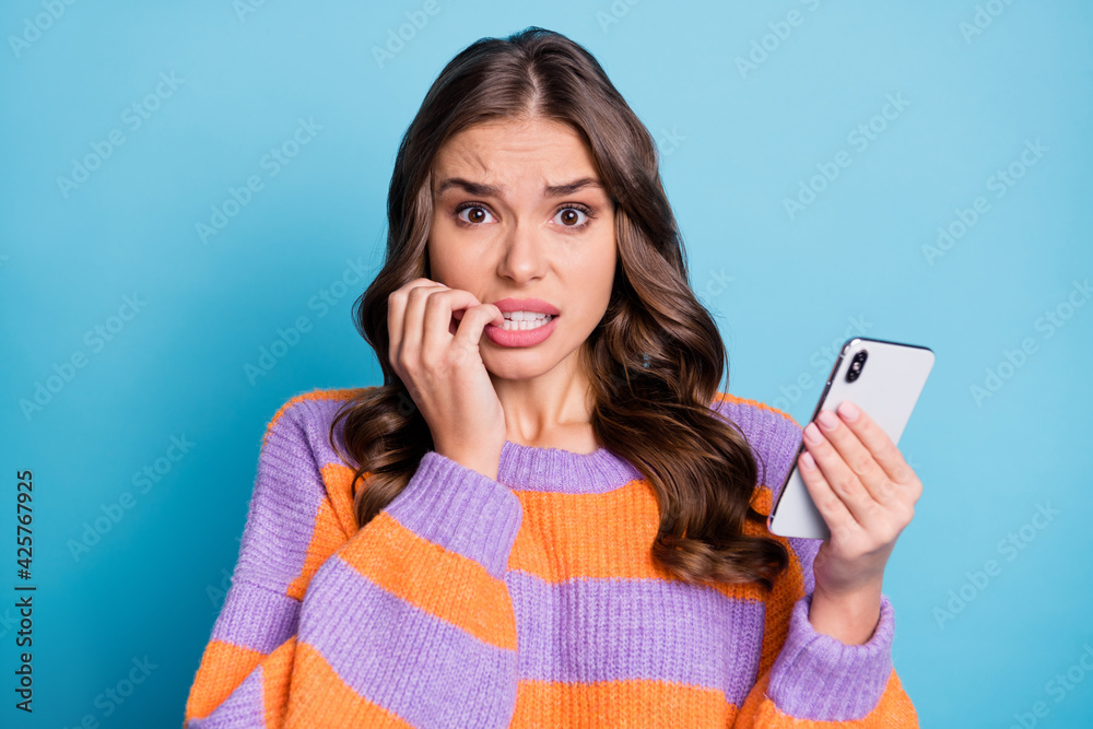 Photo of worried charming woman scared hold phone mistake post isolated on pastel blue color background