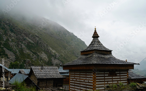 Rooftops with distinct tiles and architecture against misty Himalayas. Chitkul, India.