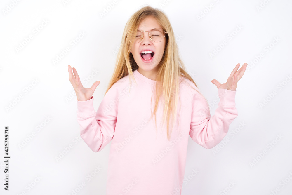 Crazy outraged Beautiful caucasian blonde little girl wearing pink sweater screams loudly and gestures angrily yells furiously. Negative human emotions feelings concept Crazy outraged Beautiful caucasian blonde little girl wearing pink sweater screams loudly and gestures angrily yells furiously. Negative human emotions feelings concept