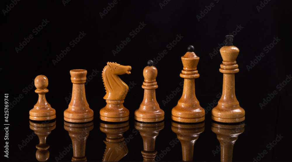 White chess pieces on a black background with a reflection. White chess pieces on a black background with a reflection.