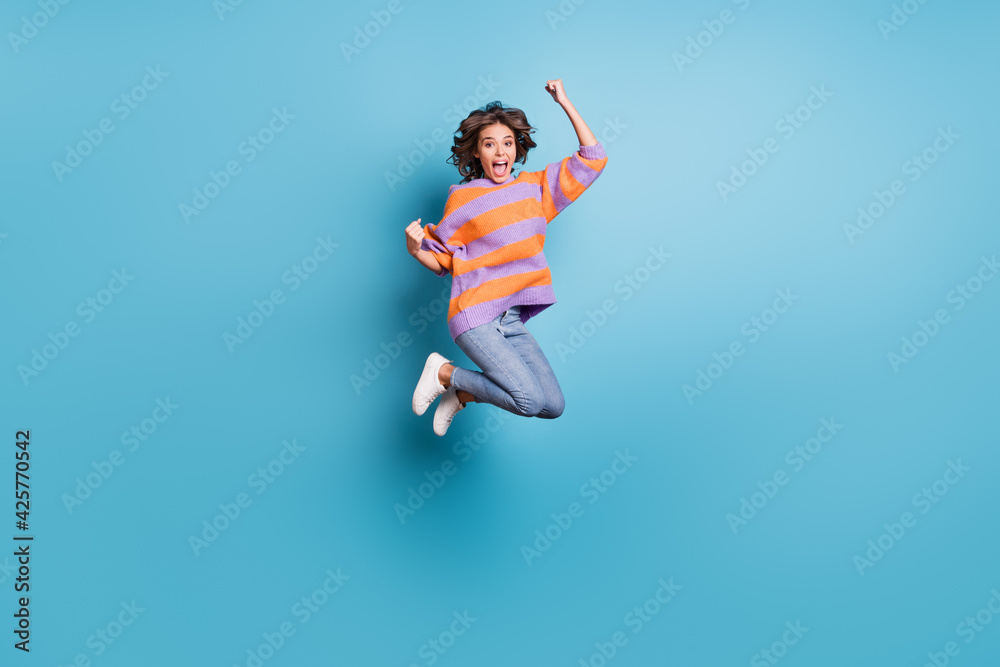 Full length body size view of attractive cheerful girl jumping rejoicing having fun isolated over bright blue color background Full length body size view of attractive cheerful girl jumping rejoicing having fun isolated over bright blue color background