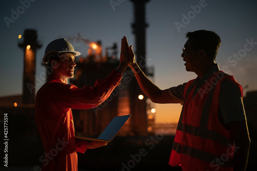 Fotografie Happy employee raise their hands and shout for joy in power plant at night