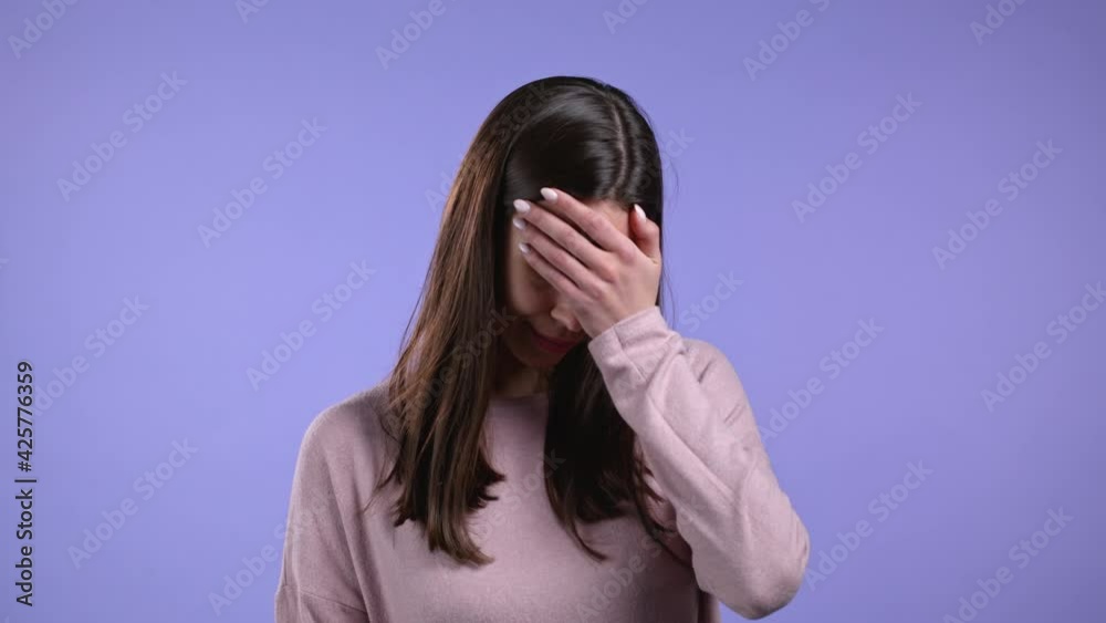 Portrait of young woman doing facepalm gesture, like no, I forgot. Unhappy woman with long hair feeling sorrow, regret, drama, failure. She isolated on violet wall Portrait of young woman doing facepalm gesture, like no, I forgot. Unhappy woman with long hair feeling sorrow, regret, drama, failure. She isolated on violet wall