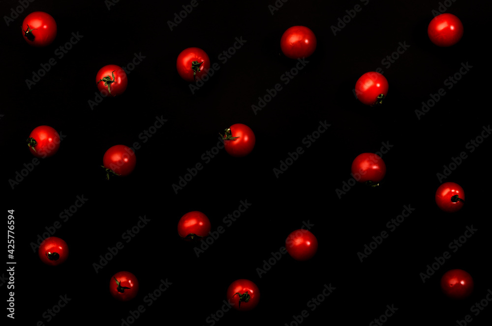 Small red cherry tomatoes on black background, top view Small red cherry tomatoes on black background, top view