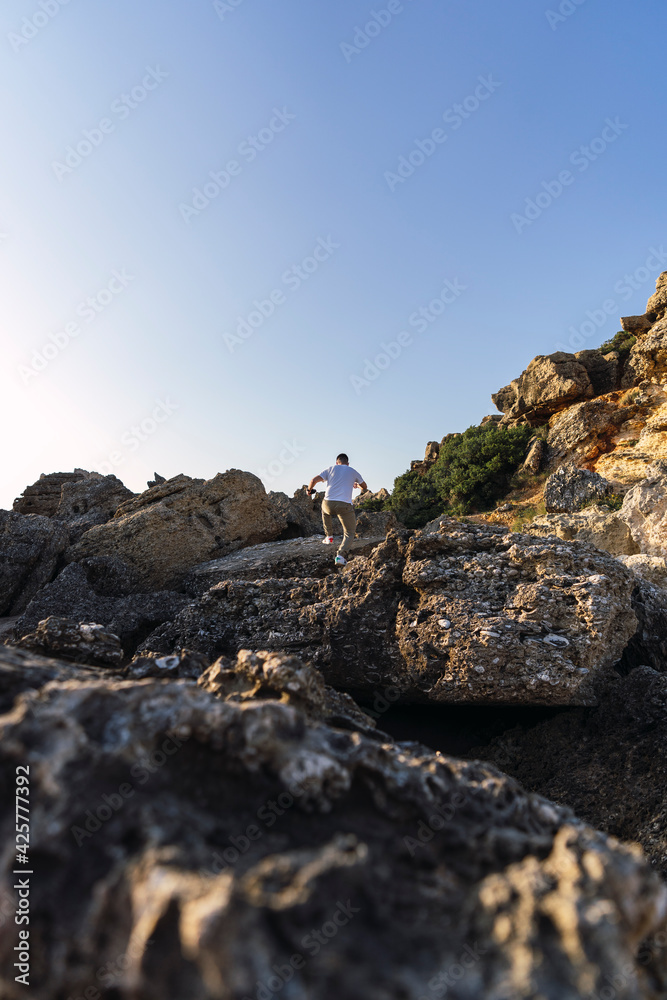 Fototapeta premium shot of a white Caucasian man walking on the rocks