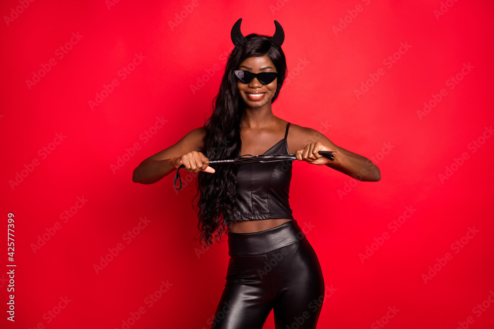 Portrait of attractive alluring cheerful girl wearing festal costume holding whip isolated over bright red color background Portrait of attractive alluring cheerful girl wearing festal costume holding whip isolated over bright red color background
