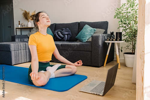 Young woman doing yoga or meditating at home.