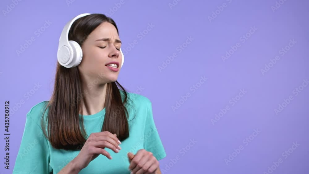 Attractive woman with white headphones on violet studio background. Cute girls portrait. Music, radio, happiness, freedom, youth concept. Attractive woman with white headphones on violet studio background. Cute girls portrait. Music, radio, happiness, freedom, youth concept.