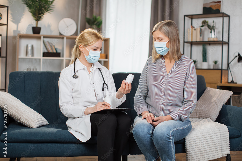 Obraz premium Seniors healthcare concept, treatment monitoring during pandemic. Caring confident woman doctor advicing her senior patient at home, talking about how to use prescribed medicines properly.