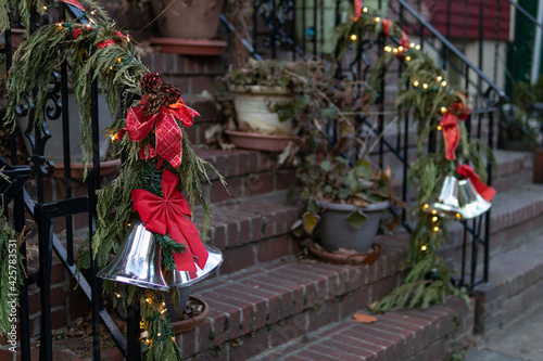 Christmas Decorations with Pine Branches Red Bows and Bells on a Stair Railing to a Home in New York City © James