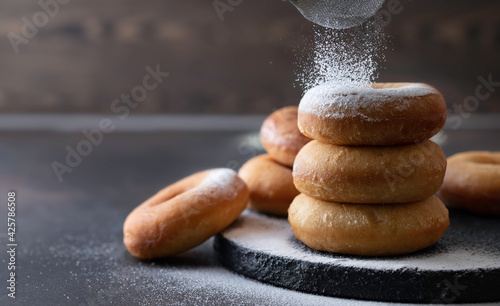 Sweet donuts with powder sugar on black background. Food concept.