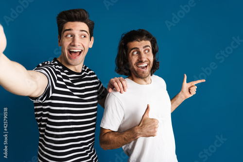 White excited two men gesturing thumbs up while taking selfie photo photo