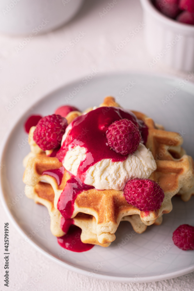 Freshly baked waffles with raspberry and ice cream on a plate Freshly baked waffles with raspberry and ice cream on a plate