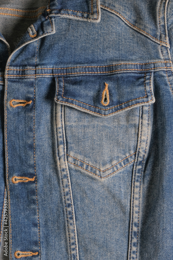 Denim pocket with a metal button on a blue jacket close-up with rough seams. High quality photo Denim pocket with a metal button on a blue jacket close-up with rough seams. High quality photo