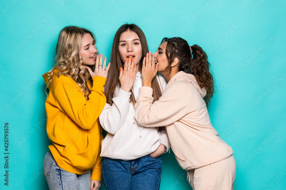 Three attractive girls gossiping isolated on turquoise background Three attractive girls gossiping isolated on turquoise background
