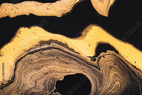 Golden slice of stone on black. Abstract liquid marble background or texture. Acrylic Fluid Art. Digital decor photo