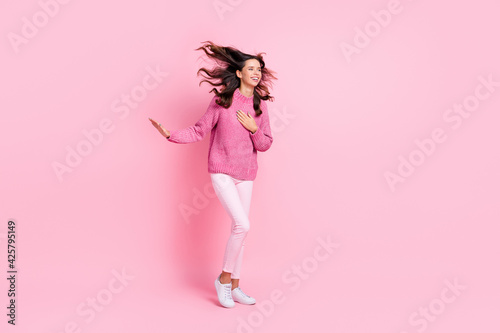 Full size photo of hooray cool brunette lady stand look empty space wear pink sweater trousers sneakers isolated on pink background