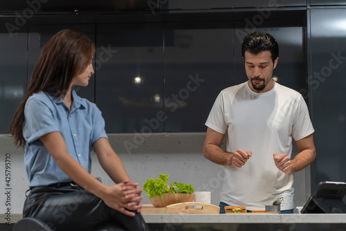 The husband makes breakfast and sandwiches in the kitchen at home so his wife can prepare for work.