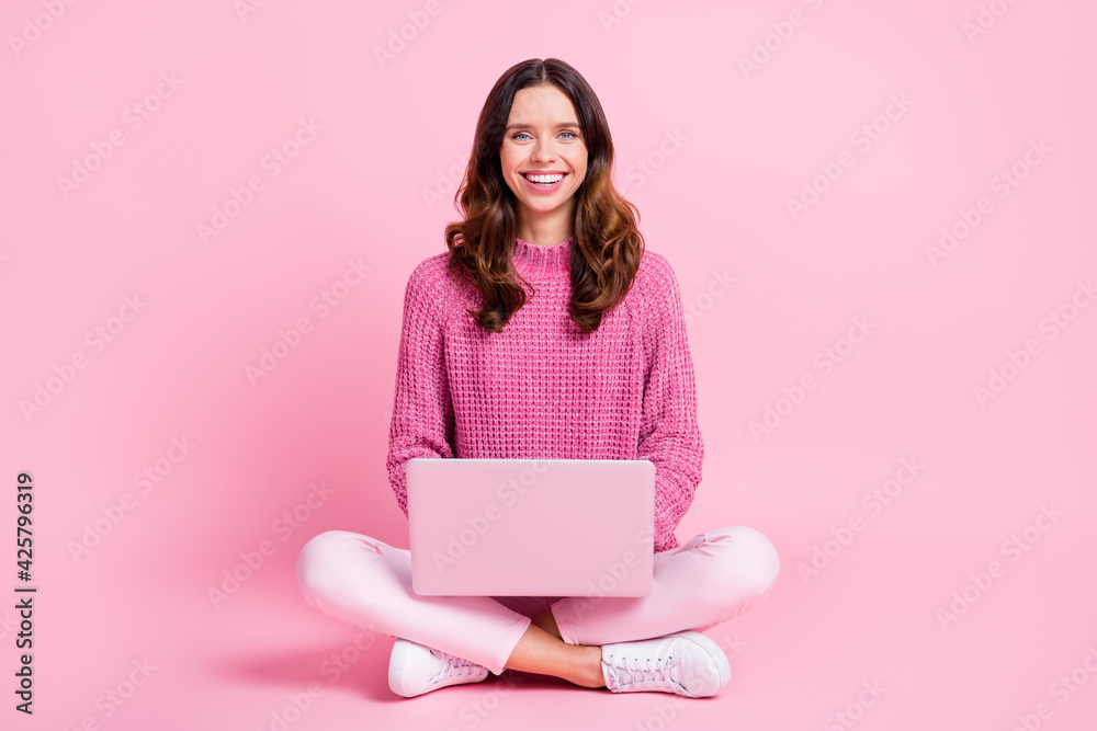 Full size photo of optimistic nice brunette lady sit type laptop wear pink sweater trousers sneakers isolated on pink background Full size photo of optimistic nice brunette lady sit type laptop wear pink sweater trousers sneakers isolated on pink background