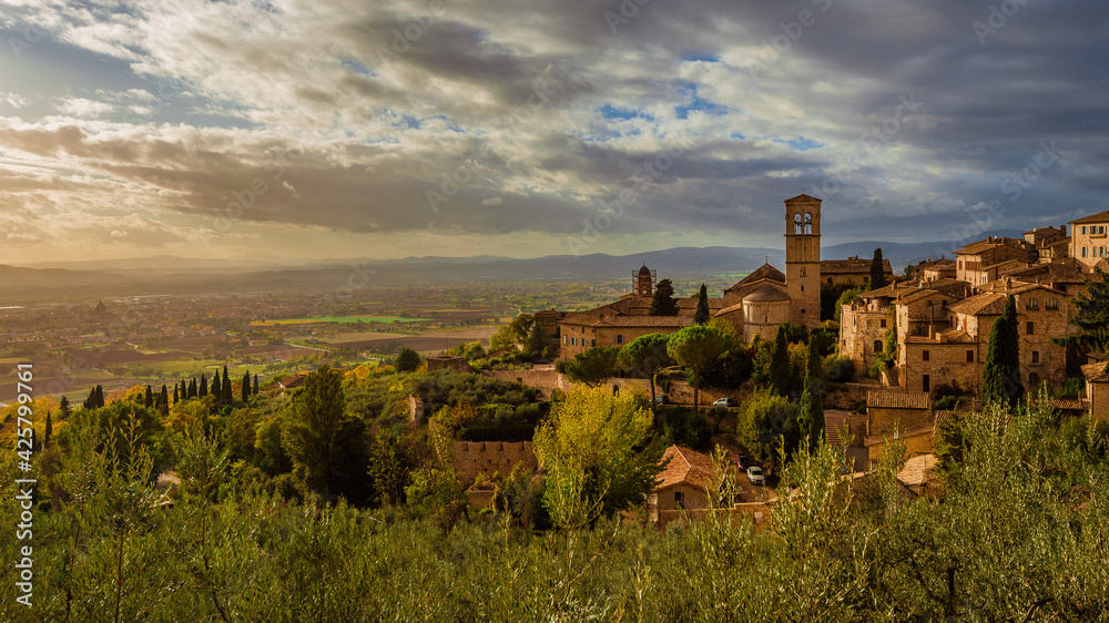 View of the Assisi historic center ancient buildings and nearby countryside at sunset with beautiful clouds