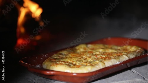 Fire is burning in the oven and the pizza or pie is being baked