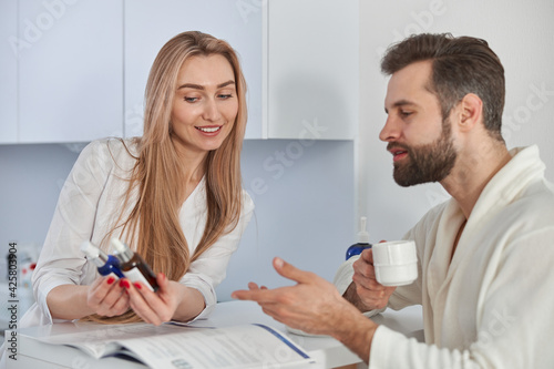 Medical worker consults with brochure and beauty treatments to patient. Patient young man standing near the reception and holding tea