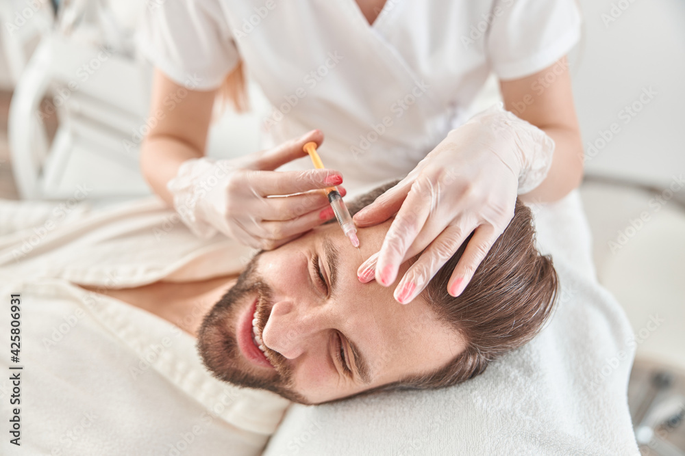 Close up makes mesotherapy injections to young man. Treatment of male by a beautician for tightening and smoothing wrinkles on the face skin