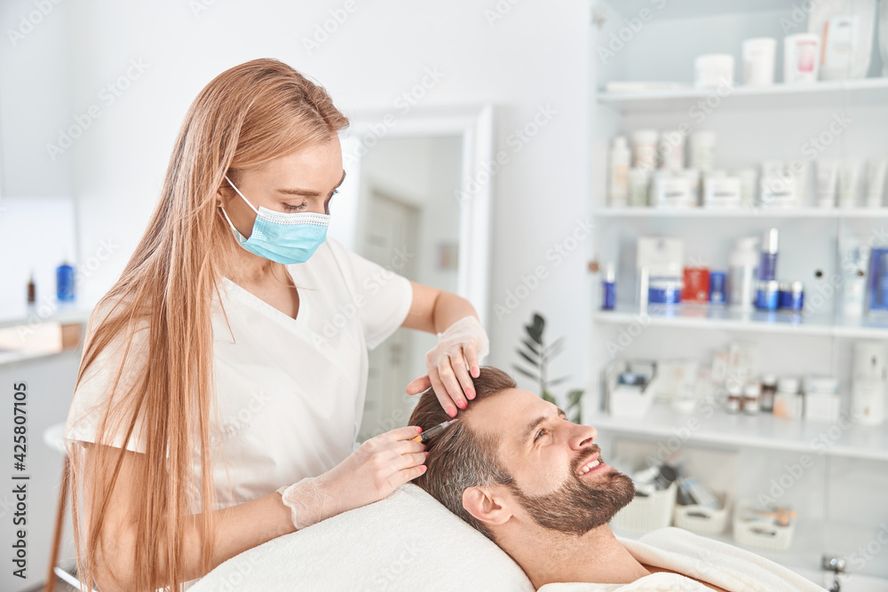 Treatment of young man by a beautician for tightening and smoothing wrinkles on the face skin. Mesotherapy injections to attractive male Treatment of young man by a beautician for tightening and smoothing wrinkles on the face skin. Mesotherapy injections to attractive male