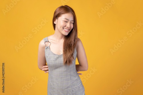 Asian girl on yellow background. Attractive young girl with happy emotion with copy space. Happy smiling young Asian girl isolated on yellow studio background. Carefree happy Asian girl.