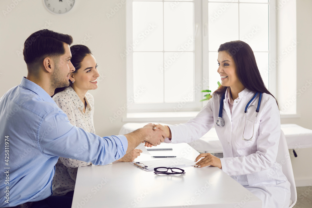 Thanks for help. Wife and husband shake hands with the woman doctor thanking her for the reception and consultation. Married couple on a medical examination in a modern clinic. Medicine concept. Thanks for help. Wife and husband shake hands with the woman doctor thanking her for the reception and consultation. Married couple on a medical examination in a modern clinic. Medicine concept.