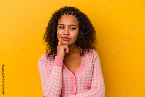 Young african american woman isolated on yellow background contemplating, planning a strategy, thinking about the way of a business.