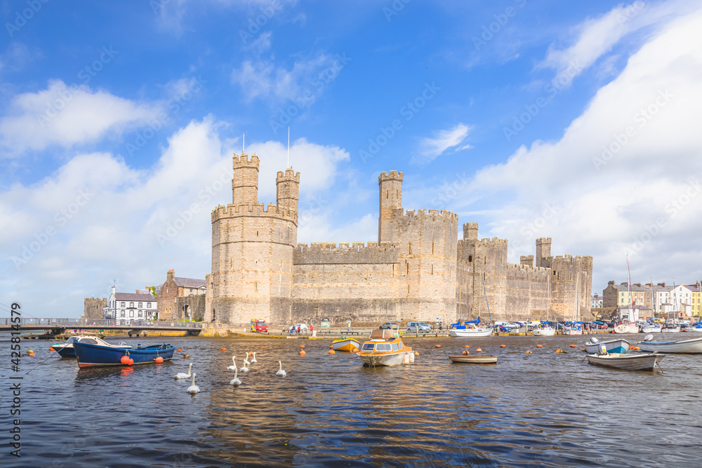 The historic medieval Caernarfon Castle on the River Seiont on a summer day in North Wales, UK.
