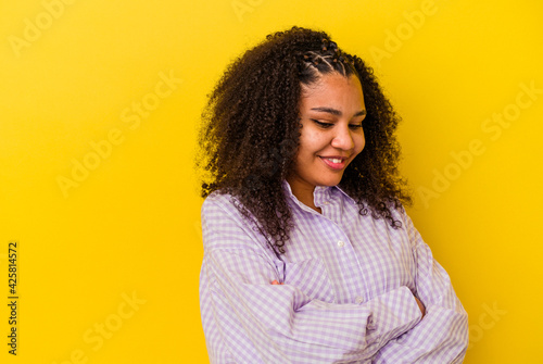 Young african american woman isolated on yellow background smiling confident with crossed arms.