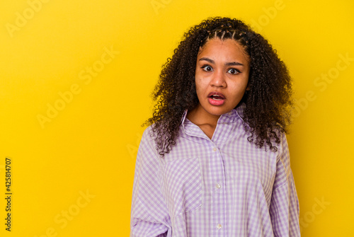 Young african american woman isolated on yellow background being shocked because of something she has seen.