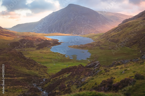 Dramatic landscape vista of Cwm Idwal in the Gyderau mountains of Snowdonia National Park in North Wales during sunset or sunrise.