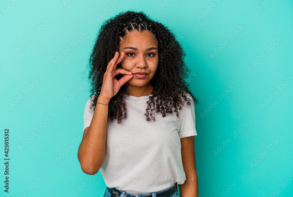 Young african american woman isolated on blue background with fingers on lips keeping a secret.