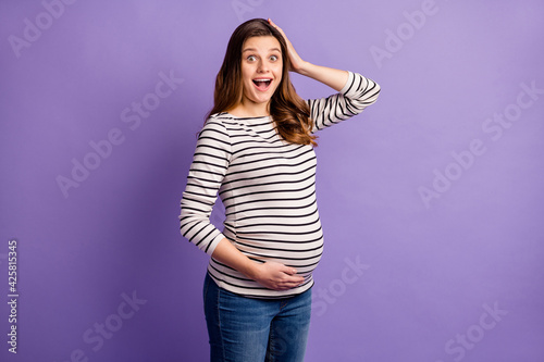 Photo of impressed funny woman expecting child wear striped shirt arm belly head open mouth isolated purple color background