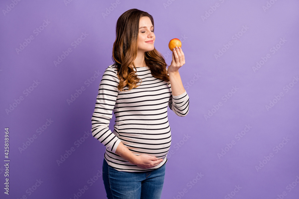 Photo of pretty dreamy lady waiting baby dressed striped shirt arm tummy enjoy fruit aroma isolated violet color background Photo of pretty dreamy lady waiting baby dressed striped shirt arm tummy enjoy fruit aroma isolated violet color background