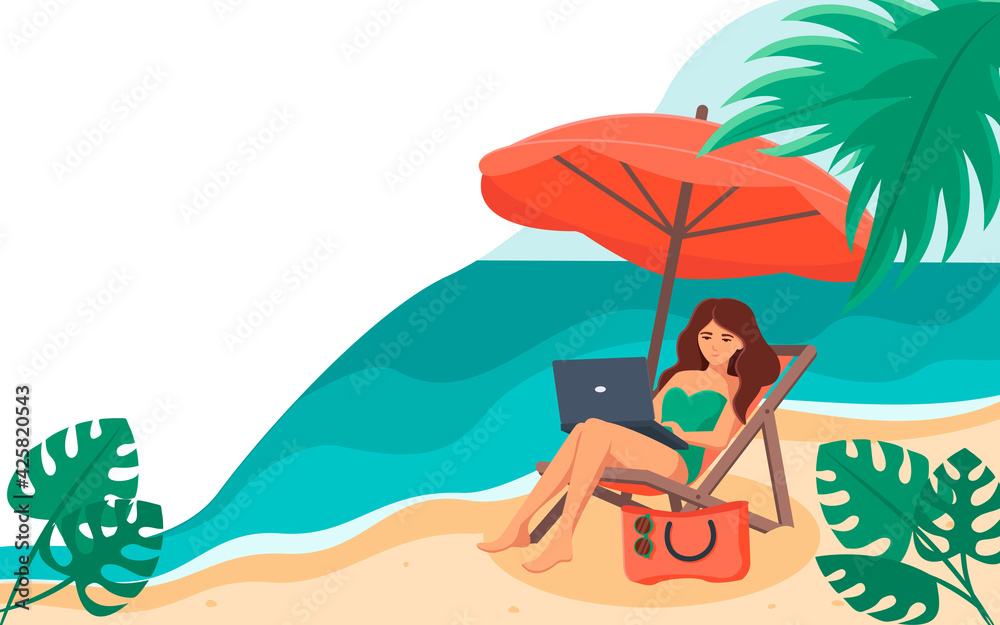 The girl is sitting on a chaise longue with a laptop on her lap, under an umbrella, against the background of the sea .