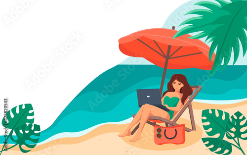 The girl is sitting on a chaise longue with a laptop on her lap  under an umbrella  against the background of the sea .