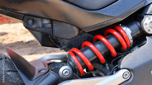 Shockbreaker rear matic motorcycle. Dirty mono shock absorber and red coil springs. Rear suspension of the motorcycle for a comfortable ride. Close focus and select an object.