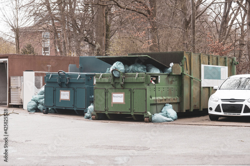 next to 2 trash compactors are numerous blue trash bags © karegg